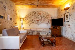 uma sala de estar com um sofá e uma televisão em Le Gerlette - La Stalla em Braccagni