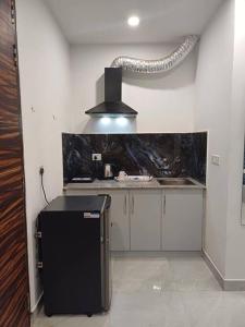 uma cozinha com um frigorífico preto num quarto em Blue house sec 46 gurgaon em Gurgaon