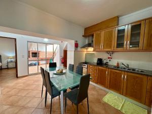 uma cozinha com uma mesa de vidro e cadeiras em Best Houses 106 - A Casa Amarela em Atouguia da Baleia