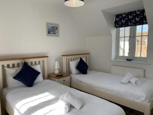 Duas camas num quarto com almofadas azuis e brancas em Norman's Nook, The Bay Filey em Filey