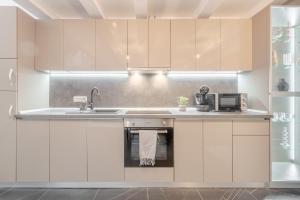 una cucina con mobili bianchi e un lavandino di Apartament Ultra-Central Lux + Free Parking + Self Check-In a Oradea