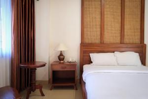 a bedroom with a bed and a table with a lamp at The Garden Suites New in Solo