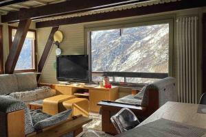 a living room with a large window and a television at Chalet charme vista panoramica sauna idromassaggio (Chalet Fanella) in Valtournenche