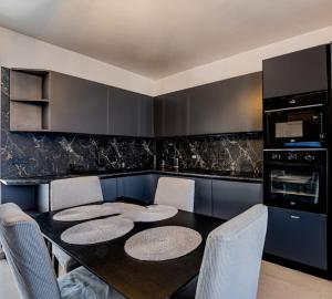 uma cozinha com uma mesa preta com cadeiras e electrodomésticos em BlissNest em Marsaskala