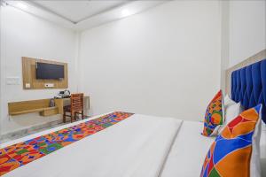 een witte kamer met een bed en een bureau bij FabHotel Taj Avenue in Tājganj