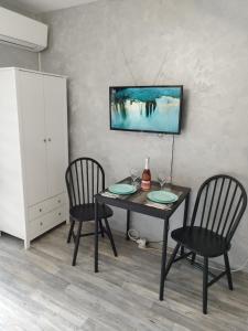 - une table à manger avec 2 chaises et une télévision murale dans l'établissement Aпартамент 5, à Varna