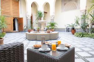 a patio with a table with food and orange juice at Riad Al Ansari in Fès