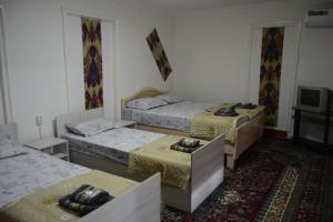 a room with three beds and a television at Orzu Guest House in Bukhara