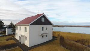 una casa blanca con techo rojo junto a un cuerpo de agua en Setrið Guesthouse, en Borgarnes