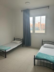 two beds in a room with a window at 2BR in Abu Dhabi-Near Airport, Shuttle Available in Abu Dhabi