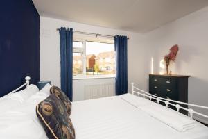 1 dormitorio con 1 cama con cortinas azules y ventana en St Lawrence, en Pittington