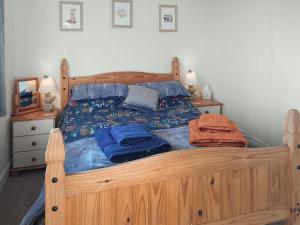 a bedroom with a wooden bed with blue sheets at Curlew Cottage in Thorpe Saint Peter