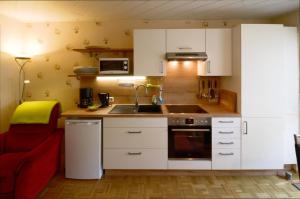 a kitchen with white cabinets and a sink and a red chair at Ferienappartment Becker Zentrum in Lauterbach