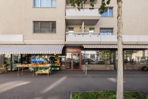 a building with a store with tables in front of it at EMA House Serviced Apartments Aussersihl in Zürich