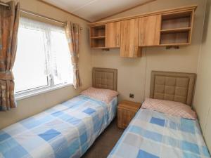two beds in a room with a window and cabinets at A La Mer in Paignton