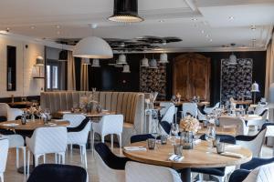 a restaurant with wooden tables and white chairs at Le Bailliage Hôtel & Spa in Salers