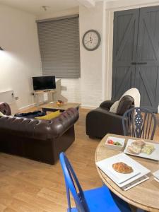 a living room with a leather couch and a table at Millside Lodge - Easy walk to Shops, Attractions, in Burton upon Trent