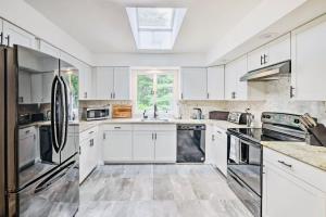 uma cozinha com armários brancos e electrodomésticos de aço inoxidável em Oasis Hot Tub Pool Game Room em Saylorsburg