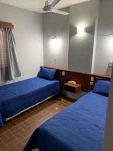 Zimmer mit 2 blauen Betten und einem Spiegel in der Unterkunft Hotel Nuevo Trento in La Banda