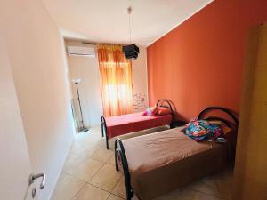 two beds in a room with orange walls at Villa Pina in Reggio Calabria