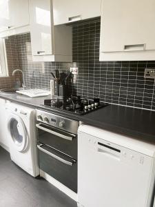 a kitchen with a stove and a washing machine at Spacious 3 Bedroom House with Garden for Reduced price - Limited time ONLY - in Westcliff-On-Sea