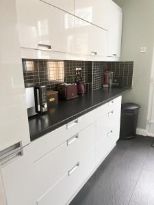 a kitchen with white cabinets and a black counter top at CLARK PROPERTY ESTATES - Southend - 3 Bedrooms - 5 Beds - Garden - Business & Leisure - Long or Short Term Enquire Today! - Sleeps 8 inc sofa beds! in Southend-on-Sea
