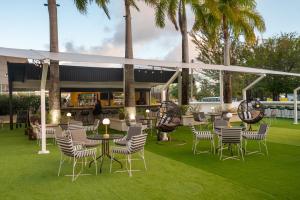 un patio con mesas, sillas y palmeras en The Rockley by Ocean Hotels - Breakfast Included, en Bridgetown