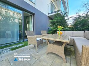 a patio with a wooden table and chairs at Przytulny Apartament z Ogrodem - 365PAM in Gąski