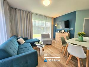 a living room with a blue couch and a table at Przytulny Apartament z Ogrodem - 365PAM in Gąski