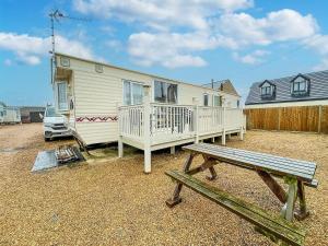 una casa con un porche y un banco frente a ella en 6 Berth Caravan In Hunstanton, Ideal For Seaside Holidays Ref 13004l, en Hunstanton