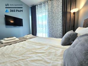 a bedroom with two beds and a tv on the wall at Przytulny Apartament z Ogrodem - 365PAM in Gąski