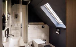 La salle de bains est pourvue de toilettes et d'un lavabo avec une lucarne. dans l'établissement Trip Inn Hotel Sachsenhausen, à Francfort-sur-le-Main