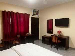 Schlafzimmer mit roten Vorhängen, einem Bett und einem Schreibtisch in der Unterkunft Amoaba's Inn in Akropong