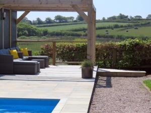 un patio con piscina y pérgola de madera en Sienna Cottage, en Bradworthy