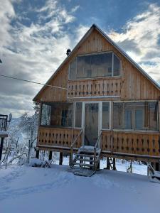 a wooden house with a porch in the snow at House in The Mountains in Khulo