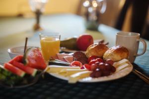 Akaciegaarden Bed & Breakfast في Hårlev: صحن من الجبن والفواكه مع كوب من عصير البرتقال