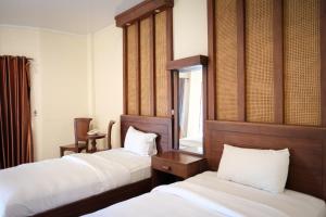 a hotel room with two beds and a window at The Garden Suites New in Solo