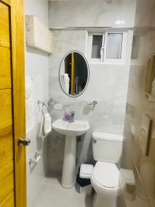 een badkamer met een toilet, een wastafel en een spiegel bij Apartamento centro de la ciudad 2 in San Pedro de Macorís