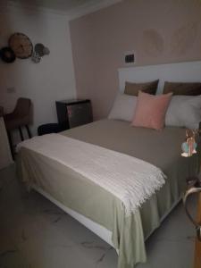 una camera da letto con un grande letto con lenzuola bianche e cuscini rosa di Apartamento centro de la ciudad 2 a San Pedro de Macorís