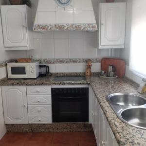 a kitchen with white cabinets and a sink and a microwave at 3 bedrooms villa with private pool furnished terrace and wifi at Encinarejo de Cordoba in Encinarejo De Córdoba