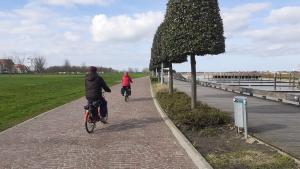 two people riding bikes down a brick path at a l'aise aan zee in Koksijde