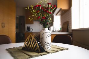 un jarrón blanco con flores sentado en una mesa en Setrið Guesthouse, en Borgarnes