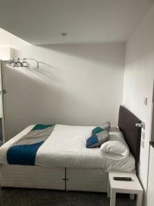 a bed in a room with a white wall at Palatine Aparthotel in Liverpool