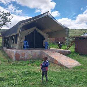 a young boy standing in front of a tent at Leruk holiday home in Masai Mara