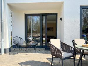 um pátio com cadeiras, uma mesa e uma porta de vidro em Luxus-Ferienhaus CASA SOL em Göhren-Lebbin