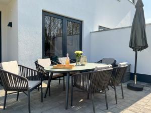 um pátio com uma mesa, cadeiras e um guarda-sol em Luxus-Ferienhaus CASA SOL em Göhren-Lebbin