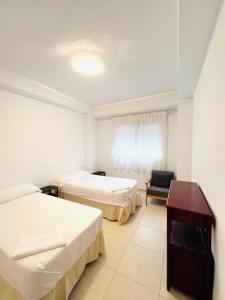 una habitación de hotel con 2 camas y una silla en Apartamento Torremar Playa, en Benicàssim