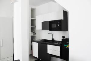 a kitchen with white cabinets and a sink and a microwave at San Leonardo Guest House in Castelbuono