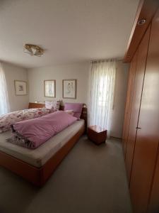 een slaapkamer met een bed met roze lakens en een raam bij Wohnung Sonnenblume in Langenargen