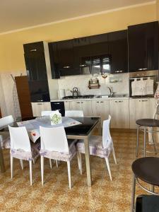 uma cozinha com uma mesa e cadeiras brancas e uma cozinha em Affittacamere La CRICOVA di Iulia em Santo Stefano